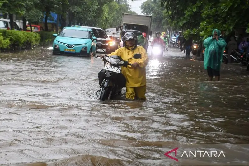 Foto: Warga mendorong motornya yang mogok saat melintasi banjir di kawasan Sunter, Jakarta Utara, Senin (12/1/2026). (ANTARA FOTO/Muhammad Adimaja/bar/pri.)