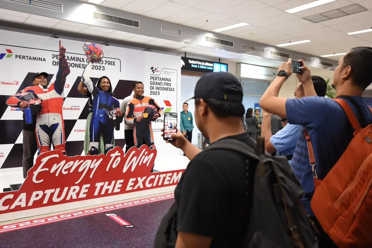 Penumpang melakukan sesi foto di booth Pertamina Grand Prix Of Indonesia 2023 di Bandara International Lombok, Lombok Tengah, Nusa Tenggara Barat pada Kamis (12/10/2023). (Foto: Istimewa)